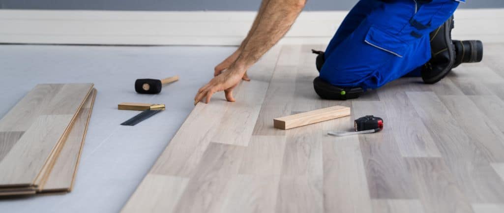 best flooring options to use when flipping a house.  A picture of a man installing vinyl flooring